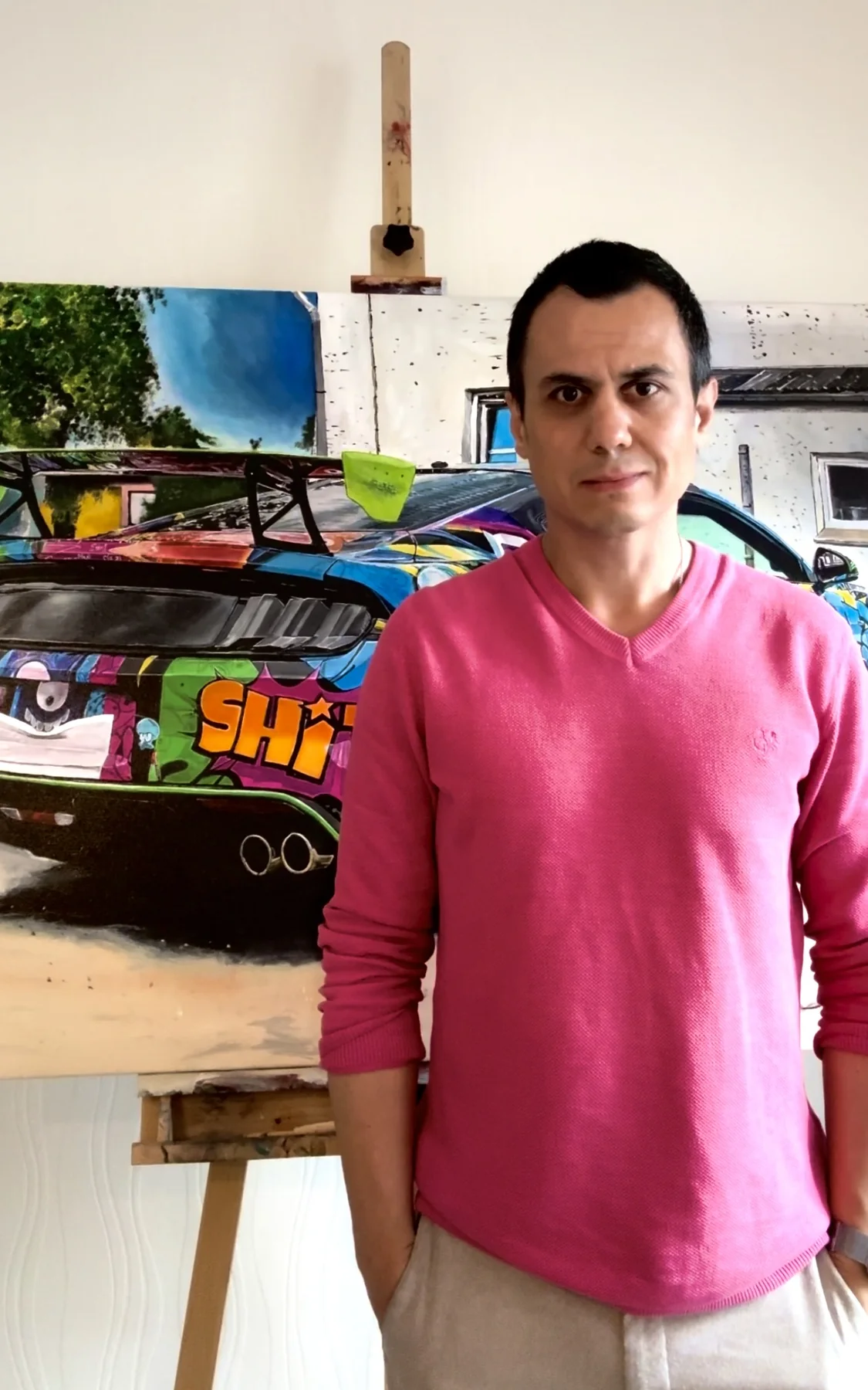 Caner Proske standing in front of The Maniac painting