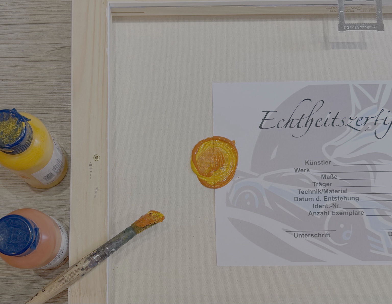 Certificate of Authenticity beside paint and brush on the back of a canvas