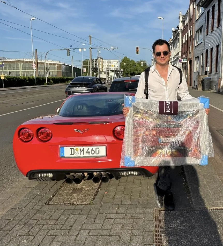 Completed red Corvette painting handed over beside the car