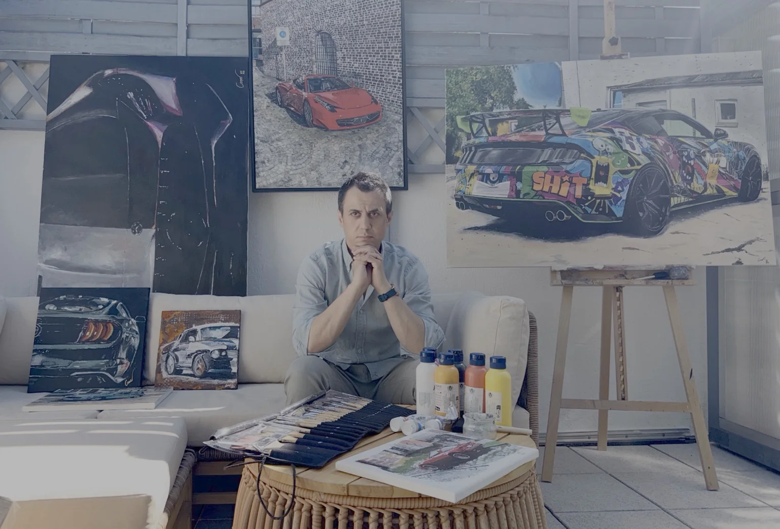Caner Proske in his studio surrounded by automotive paintings