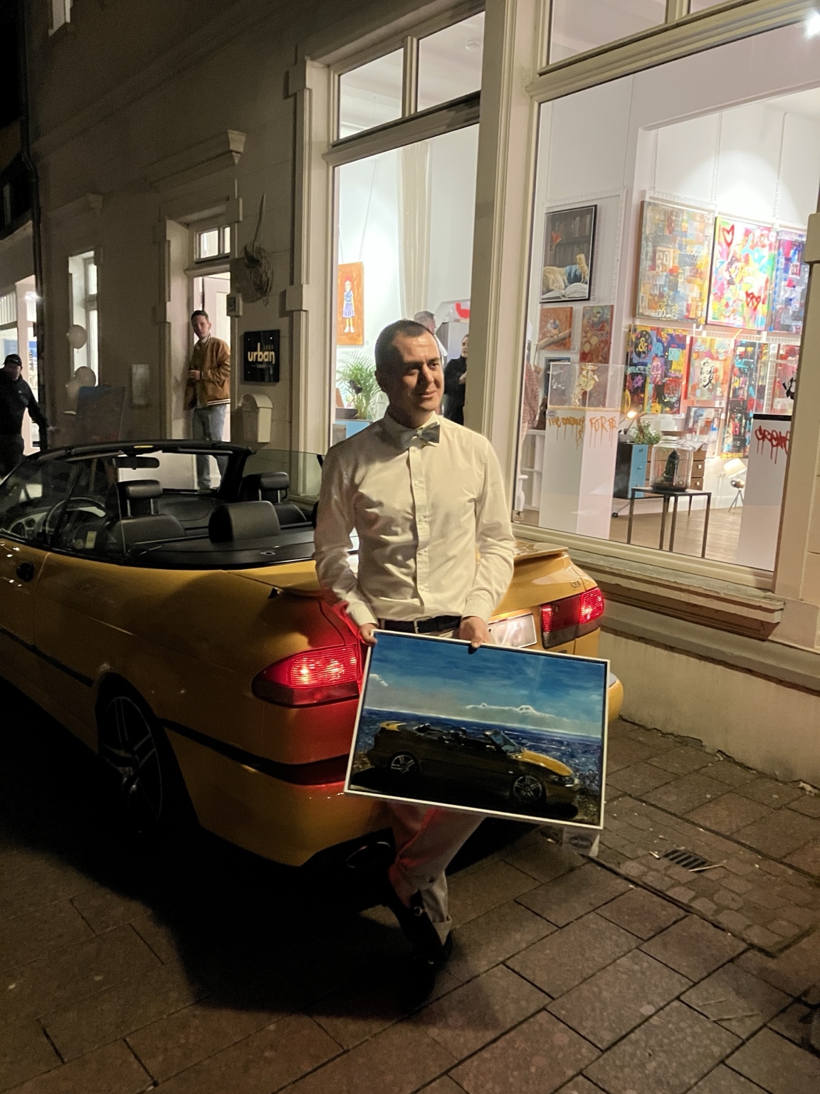 Caner Proske with his Saab painting and the car outside the gallery during the March 2026 exhibition