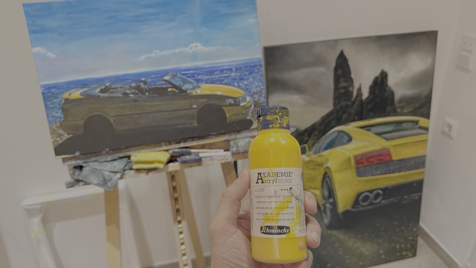 Cadmium yellow acrylic paint in the studio with two automotive paintings